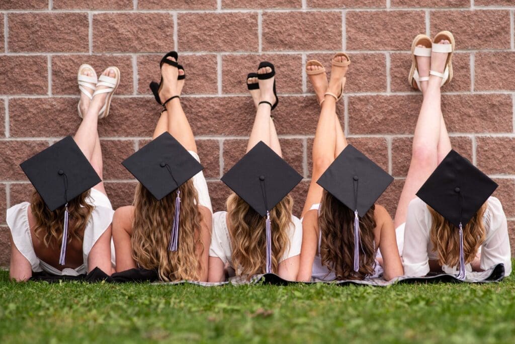 graduates with their feet on a wall 